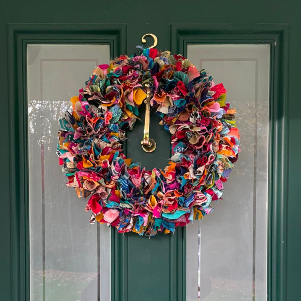 Colorful wreath on a green door with a gold doorknob