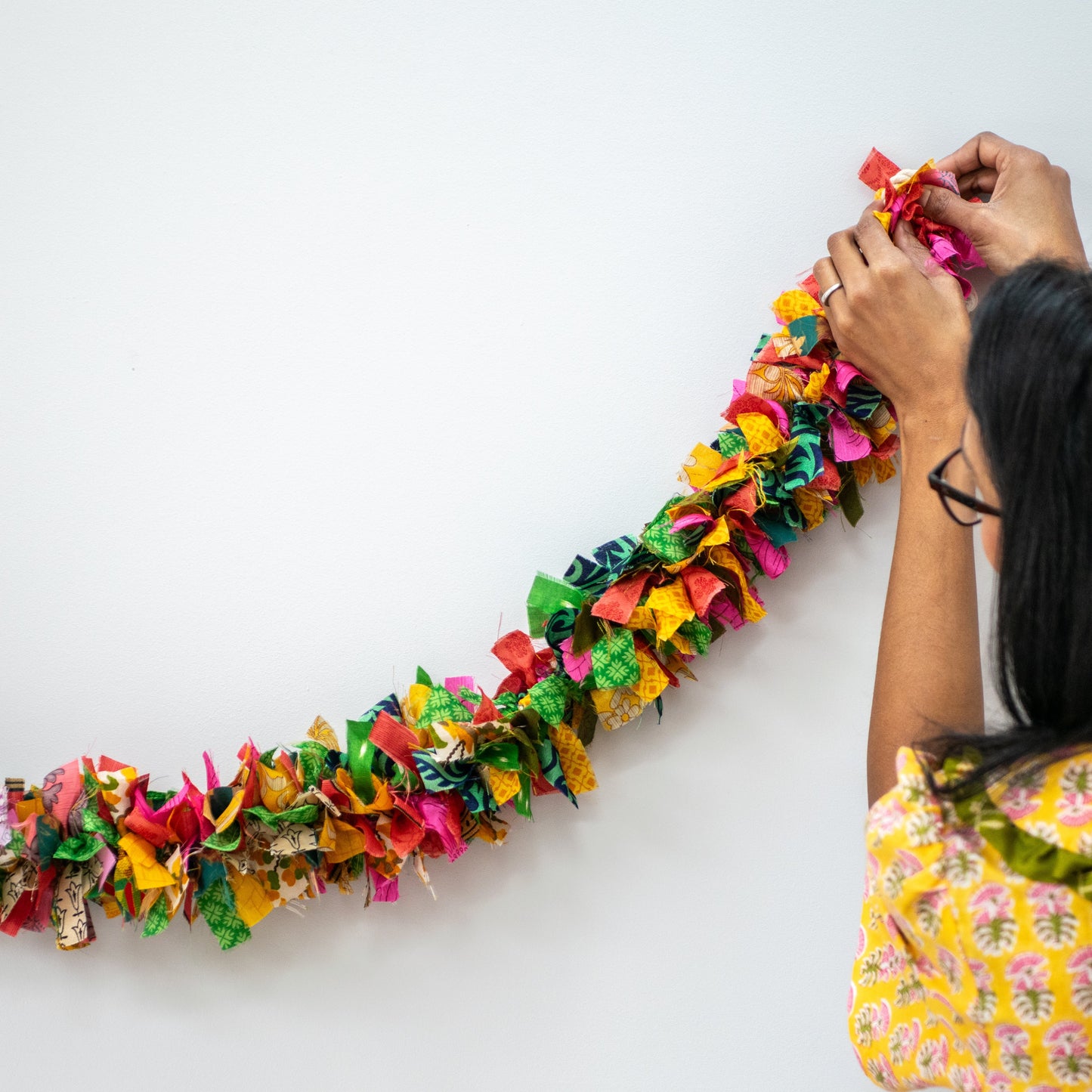 Person arranging colorful paper garland on a white background