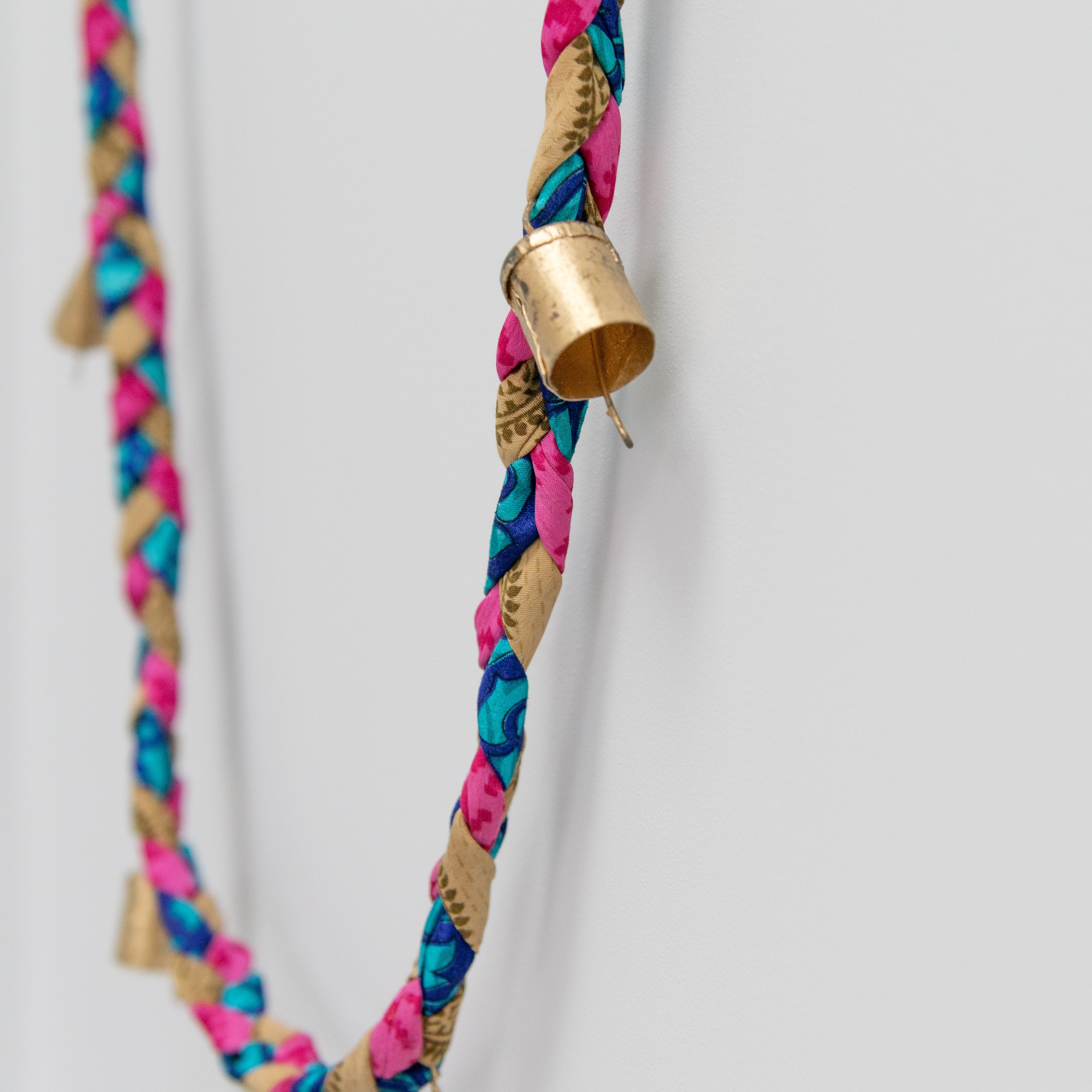 Colorful braided cord with gold cap on a white background