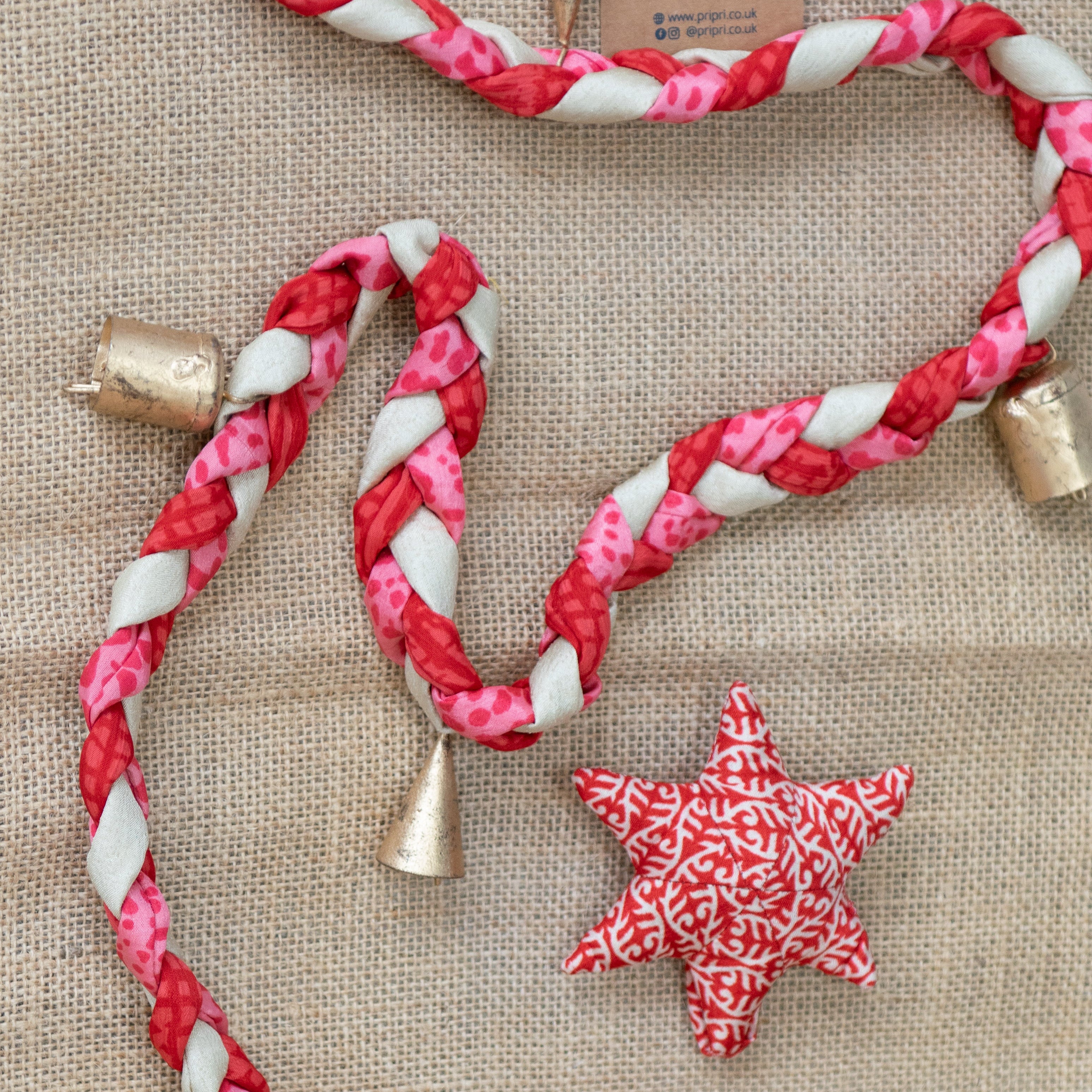 Red and white braided rope with gold bells and star-shaped decorations on a textured surface.