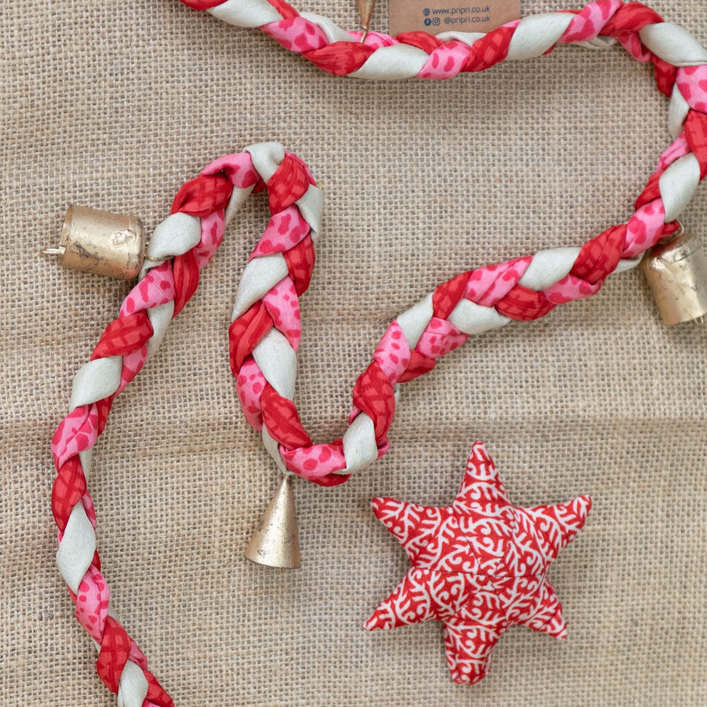 Red and white braided rope with gold bells and star-shaped decorations on a textured surface.