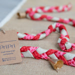 Braided garland with pink, white, and beige pattern on a textured surface with a 'PriPri' tag.