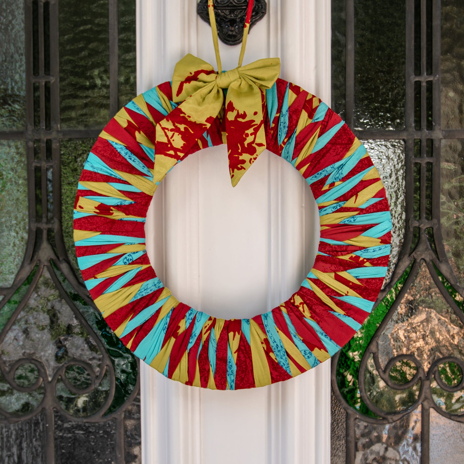Colorful wreath hanging on a door with decorative ironwork