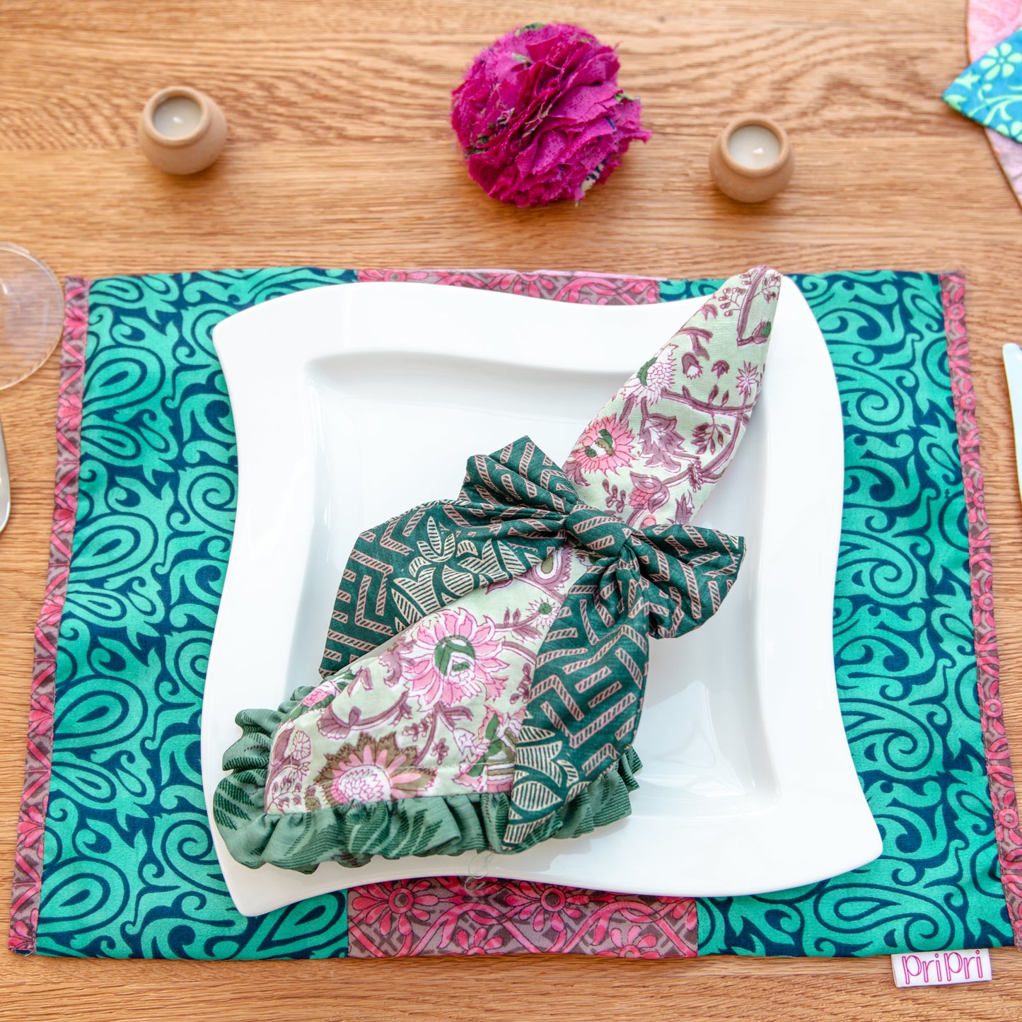 Decorative table setting with a patterned napkin and placemat on a wooden table.