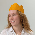 Person wearing a yellow crown hat against a plain background