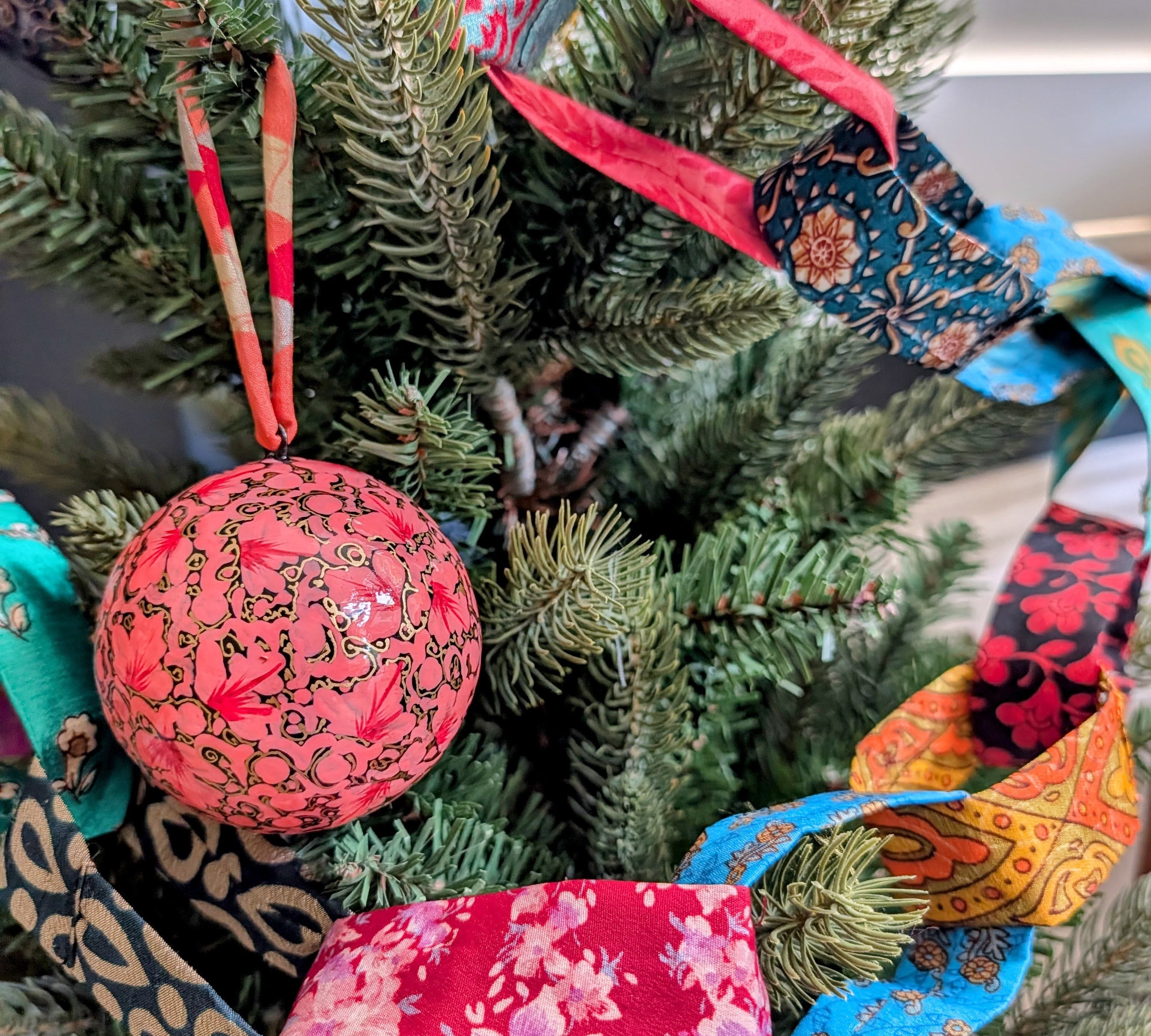 colourful fabric chain draped on a christmas tree with a pink bauble