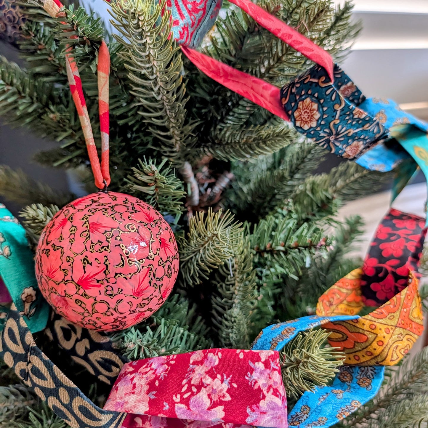 colourful fabric chain draped on a christmas tree with a pink bauble
