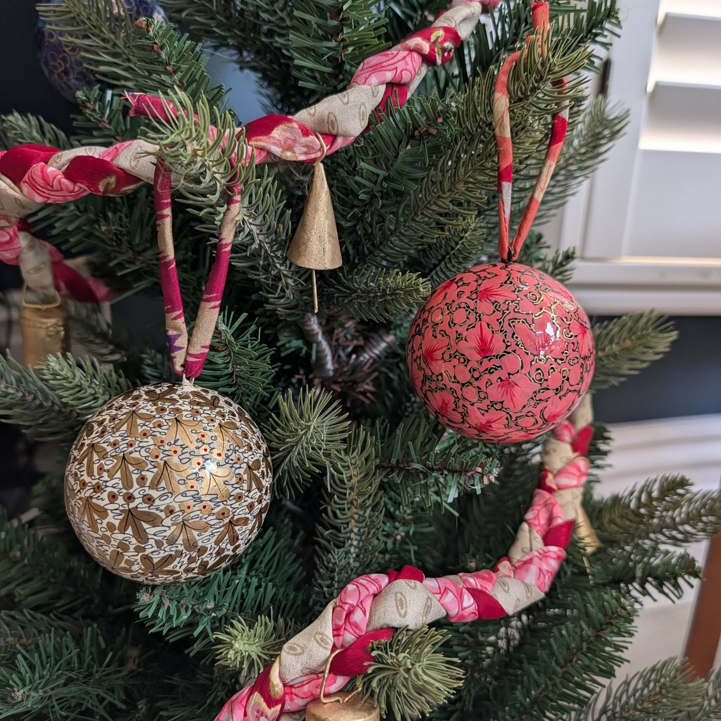 gold and pink baubles on a christmas tree with a colourful garland