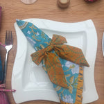 Dining table setting with a napkin, cutlery, and decorative elements on a wooden surface.