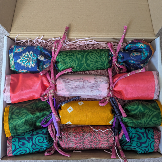 Box containing colourful fabric rolls shaped into christmas cracker shapes