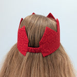 Red sari crown on a person with light brown hair against a light background