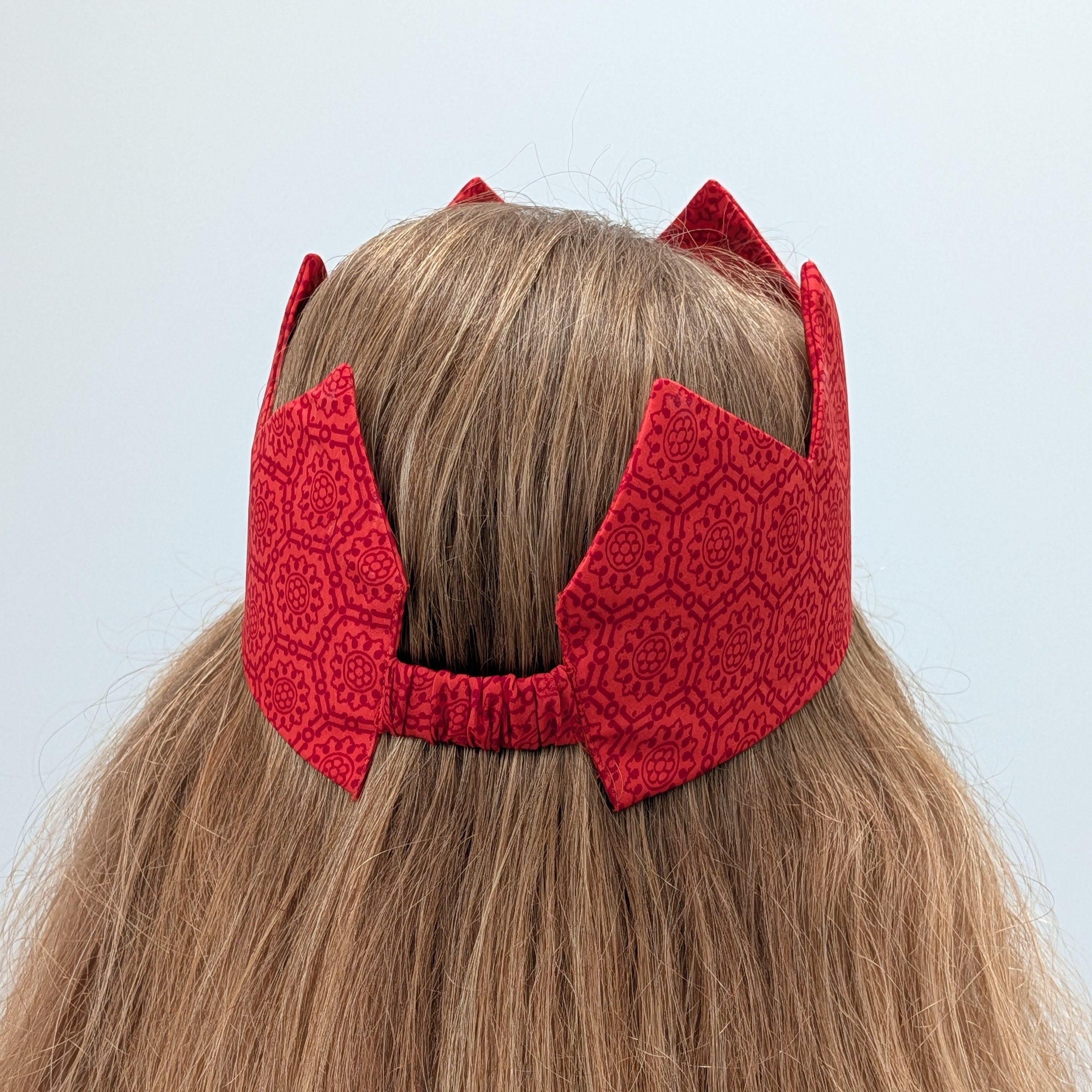 Red sari crown on a person with light brown hair against a light background