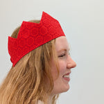 Person wearing a red sari crown against a plain background