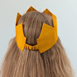 Yellow crown hat on a person's head against a light gray background